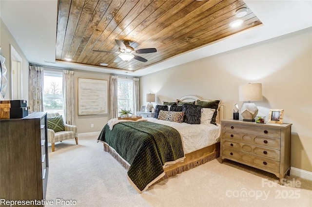 bedroom featuring wood ceiling, light colored carpet, a tray ceiling, and ceiling fan