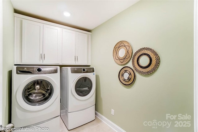 clothes washing area with cabinets and washer and clothes dryer