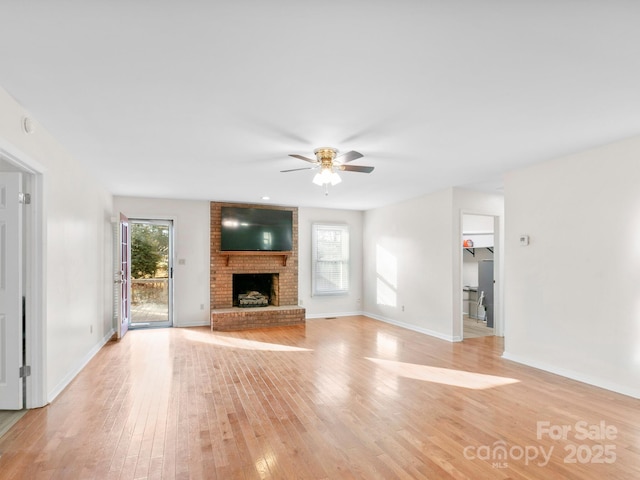 unfurnished living room featuring ceiling fan, a brick fireplace, and light hardwood / wood-style flooring