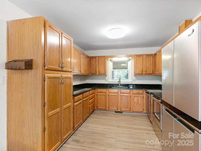 kitchen featuring appliances with stainless steel finishes, light hardwood / wood-style floors, and sink