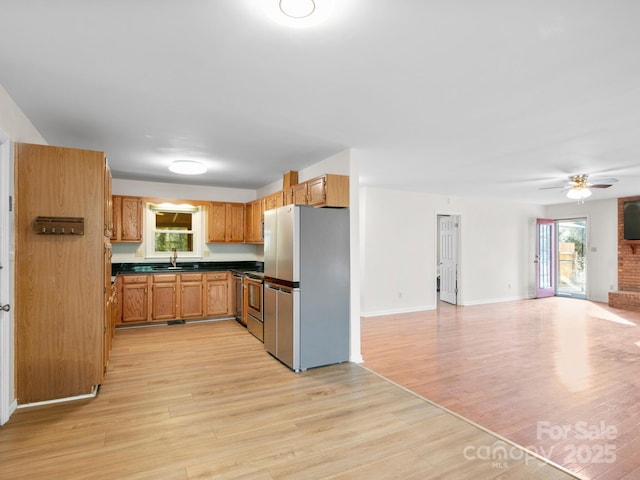 kitchen featuring ceiling fan, appliances with stainless steel finishes, sink, and light wood-type flooring