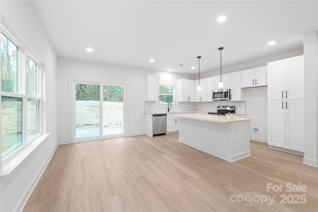 kitchen featuring sink, white cabinetry, a center island, pendant lighting, and stainless steel appliances