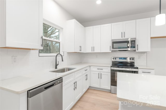 kitchen with sink, decorative light fixtures, stainless steel appliances, and white cabinets