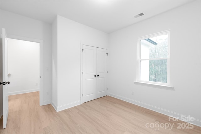 unfurnished bedroom with light hardwood / wood-style floors and a closet