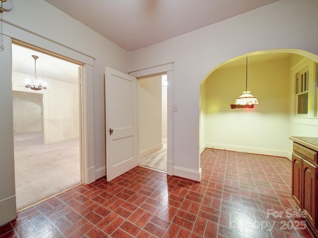 113 2nd St, Spencer, NC 28159 - unfurnished dining area featuring brick patterned flooring, arched walkways, baseboards, and a chandelier