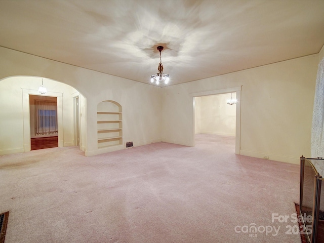 113 2nd St, Spencer, NC 28159 - empty room with arched walkways, carpet floors, a chandelier, built in shelves, and baseboards