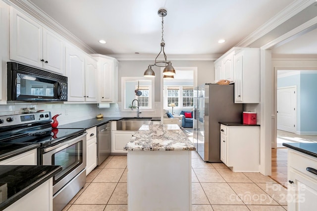 kitchen featuring pendant lighting, appliances with stainless steel finishes, white cabinetry, a kitchen island, and dark stone counters