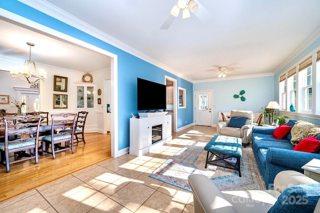 living room featuring crown molding, ceiling fan with notable chandelier, and light tile patterned floors