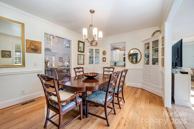 dining area featuring an inviting chandelier, crown molding, and light wood-type flooring