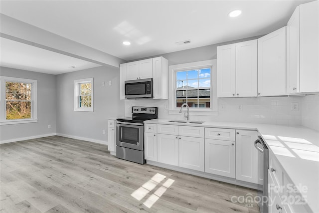 kitchen with white cabinetry, sink, stainless steel appliances, and a healthy amount of sunlight