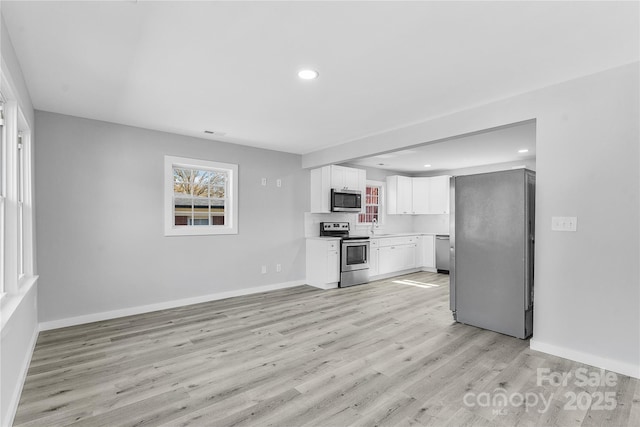 kitchen featuring stainless steel appliances, white cabinetry, sink, and light wood-type flooring