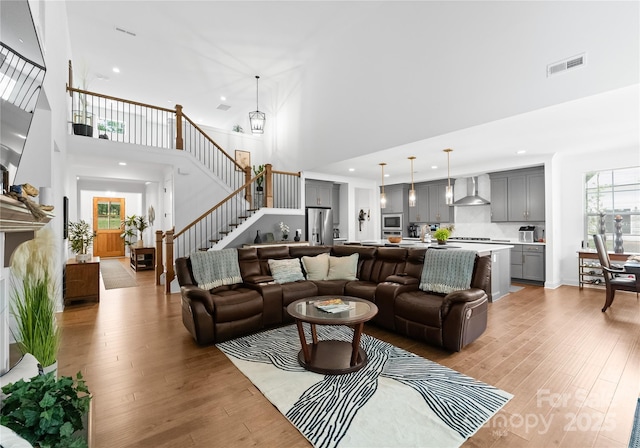 living room featuring a notable chandelier, light hardwood / wood-style flooring, and a high ceiling