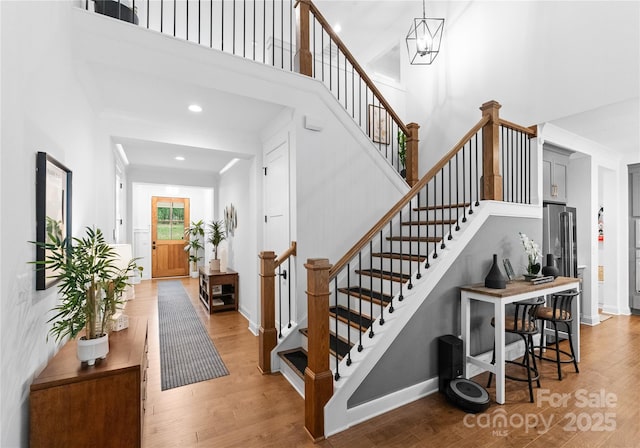 stairs with hardwood / wood-style flooring and a towering ceiling