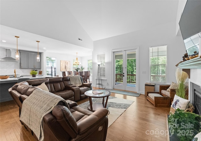 living room with french doors, high vaulted ceiling, and light hardwood / wood-style flooring