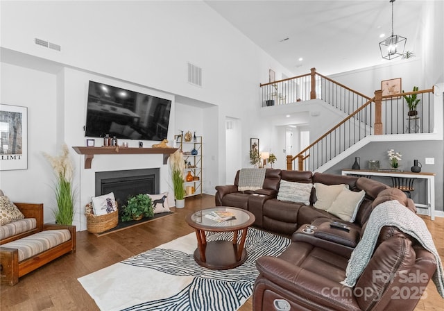 living room with a towering ceiling, hardwood / wood-style floors, and a notable chandelier