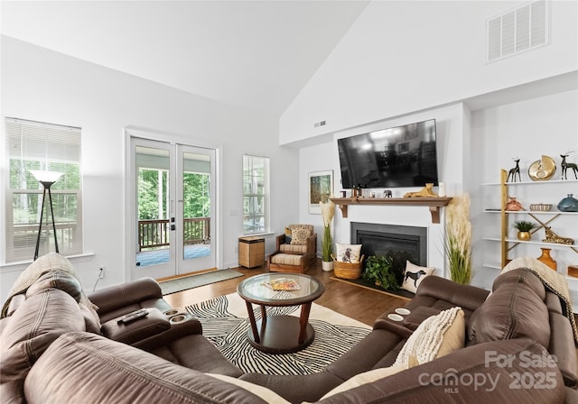 living room with french doors, high vaulted ceiling, and hardwood / wood-style floors