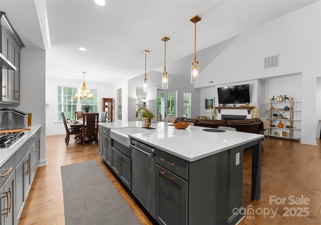 kitchen featuring stainless steel appliances, sink, a center island with sink, and decorative light fixtures