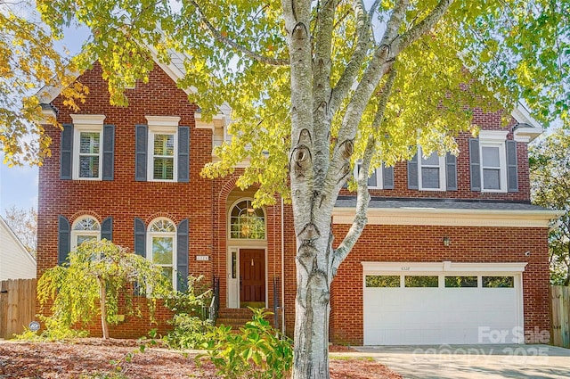 traditional-style home with concrete driveway, brick siding, fence, and an attached garage