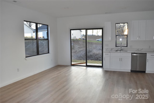 kitchen with a wealth of natural light, dishwasher, sink, white cabinets, and light wood-type flooring