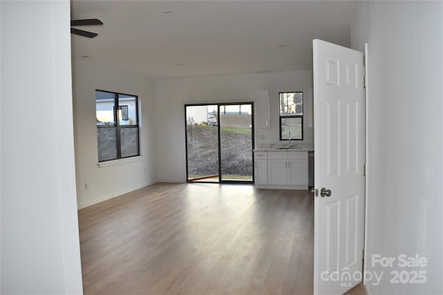 spare room with a healthy amount of sunlight, sink, and light wood-type flooring