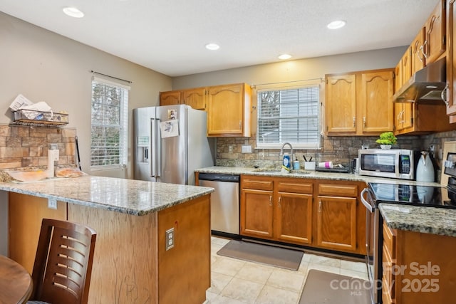 kitchen with appliances with stainless steel finishes, light stone countertops, sink, and backsplash