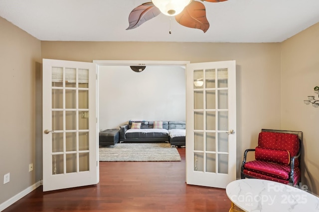 living area featuring french doors, ceiling fan, and dark hardwood / wood-style flooring