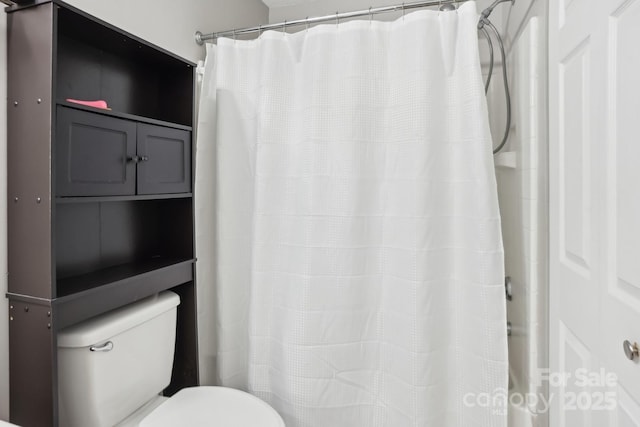 bathroom featuring toilet and curtained shower