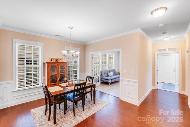 dining room with crown molding, dark wood-type flooring, and an inviting chandelier