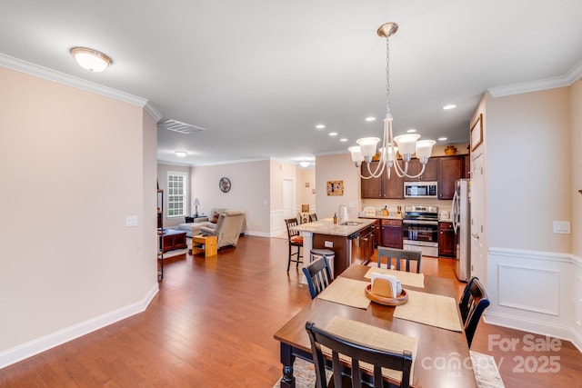 dining room featuring dark hardwood / wood-style flooring, sink, ornamental molding, and a chandelier