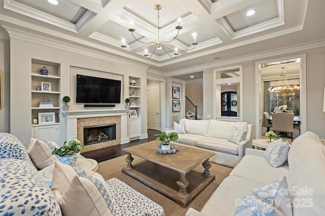 living room featuring coffered ceiling, an inviting chandelier, ornamental molding, a fireplace, and hardwood / wood-style floors