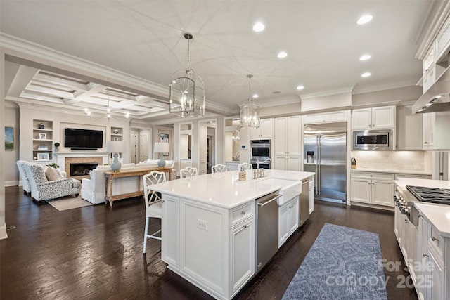 kitchen featuring a breakfast bar, white cabinetry, built in appliances, a kitchen island, and pendant lighting