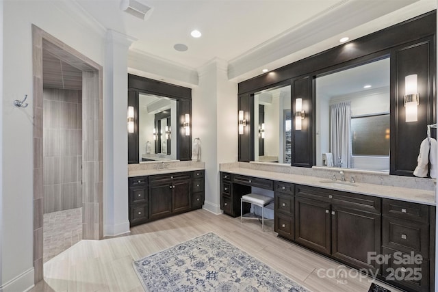 bathroom with crown molding, vanity, and a tile shower