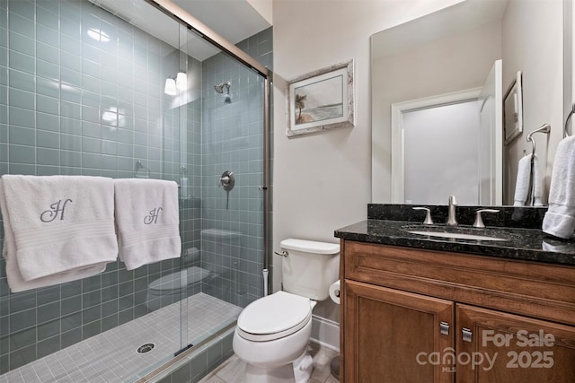 bathroom featuring vanity, toilet, and a shower with shower door