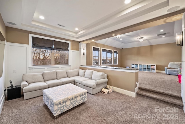 carpeted living room with a tray ceiling