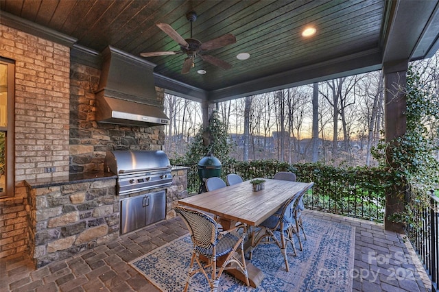 patio terrace at dusk with ceiling fan, an outdoor kitchen, and grilling area