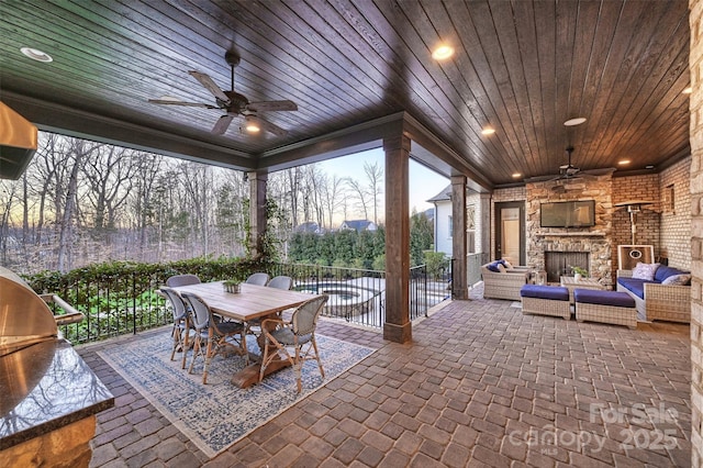 view of patio / terrace with an outdoor living space with a fireplace and ceiling fan