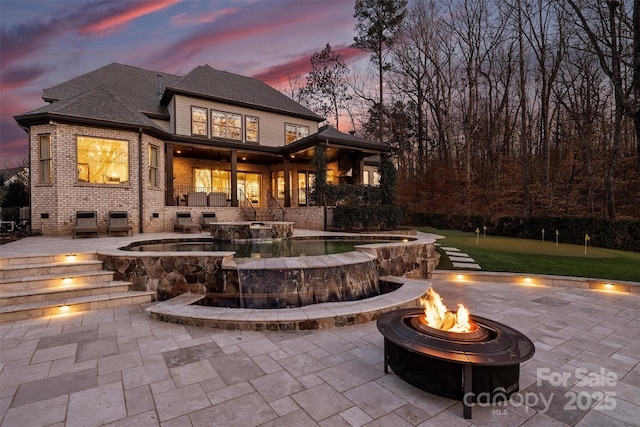 back house at dusk featuring a patio and an outdoor fire pit