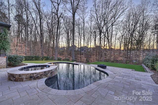 pool at dusk with a patio and a yard