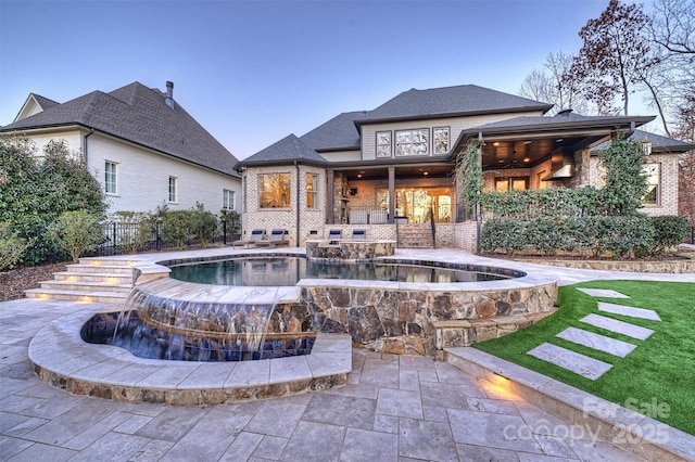 back house at dusk with ceiling fan, a swimming pool with hot tub, and a patio area