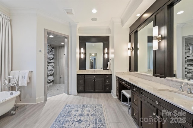 full bath with a freestanding bath, baseboards, a sink, and crown molding