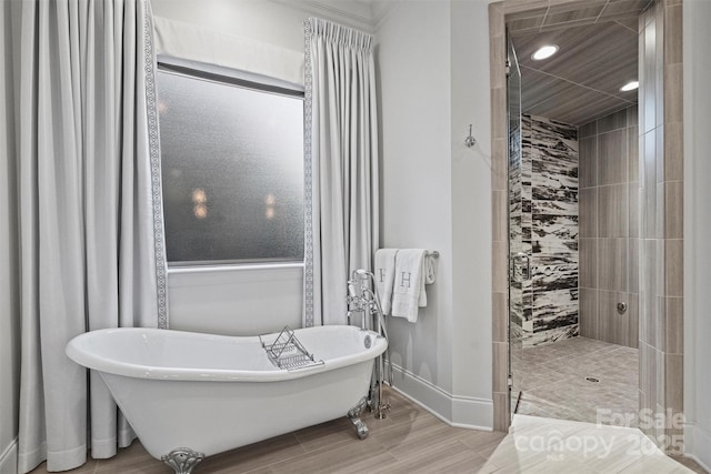 full bathroom featuring recessed lighting, a freestanding tub, tiled shower, and baseboards