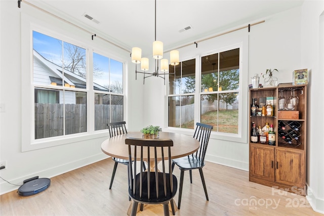 dining area featuring light wood-type flooring, a wealth of natural light, and a notable chandelier