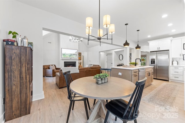 dining room featuring light hardwood / wood-style floors, vaulted ceiling, and sink