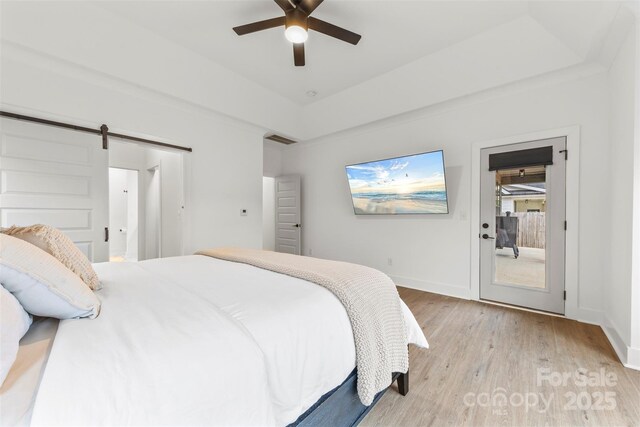 bedroom featuring light hardwood / wood-style flooring, ceiling fan, and a barn door