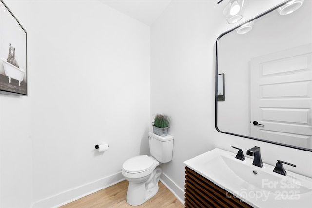 bathroom with toilet, vanity, and wood-type flooring