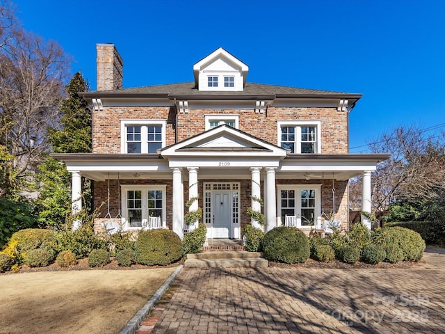 view of front facade with french doors, brick siding, and a porch