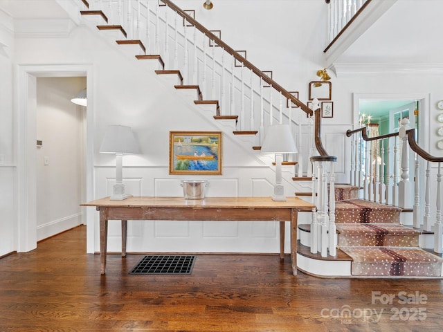 stairs featuring crown molding, a high ceiling, baseboards, and wood finished floors