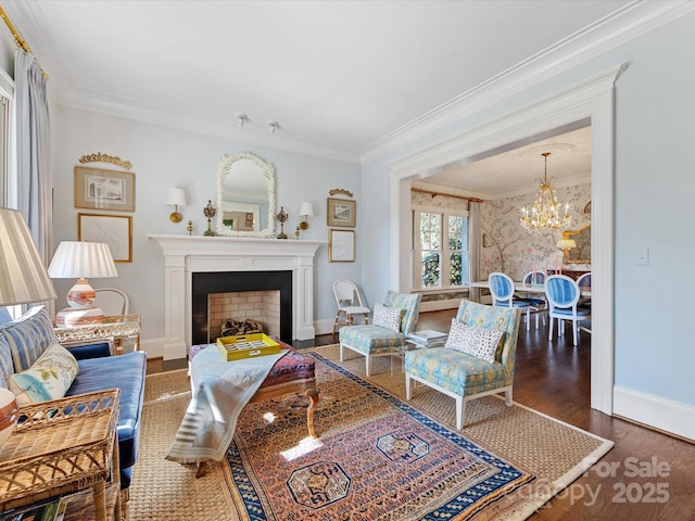living area featuring a fireplace, a chandelier, baseboards, wood finished floors, and ornamental molding
