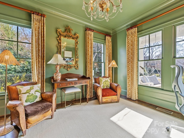living area with a healthy amount of sunlight, ornamental molding, visible vents, and a chandelier