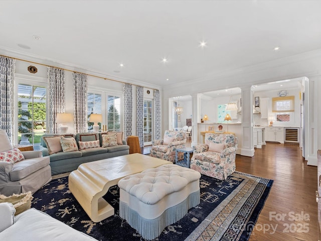 living area with crown molding, a healthy amount of sunlight, and dark wood-type flooring